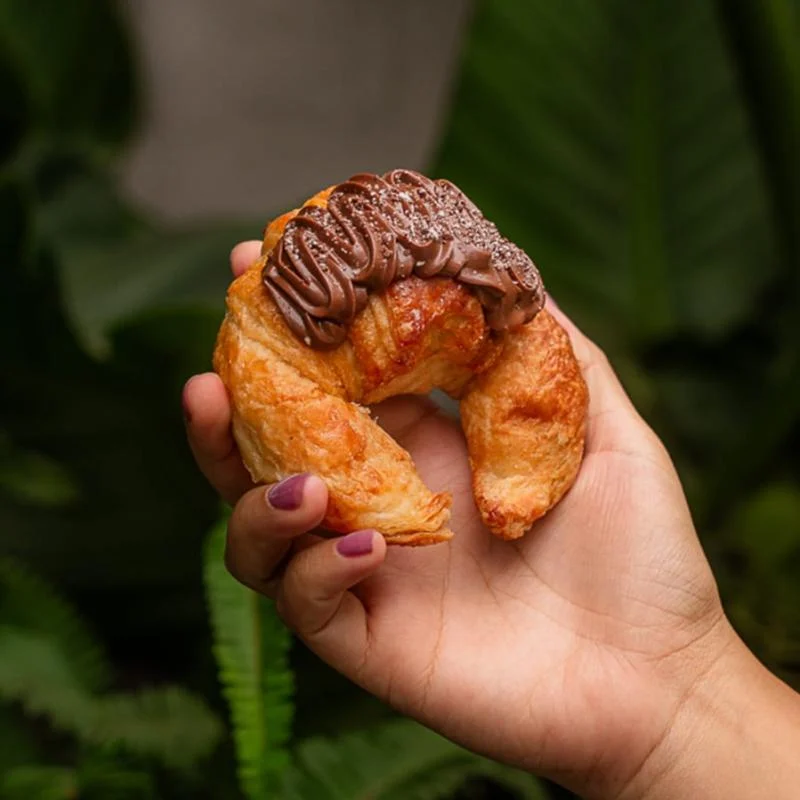 Medialuna de Porteños bañada en chocolate, sostenida en una mano